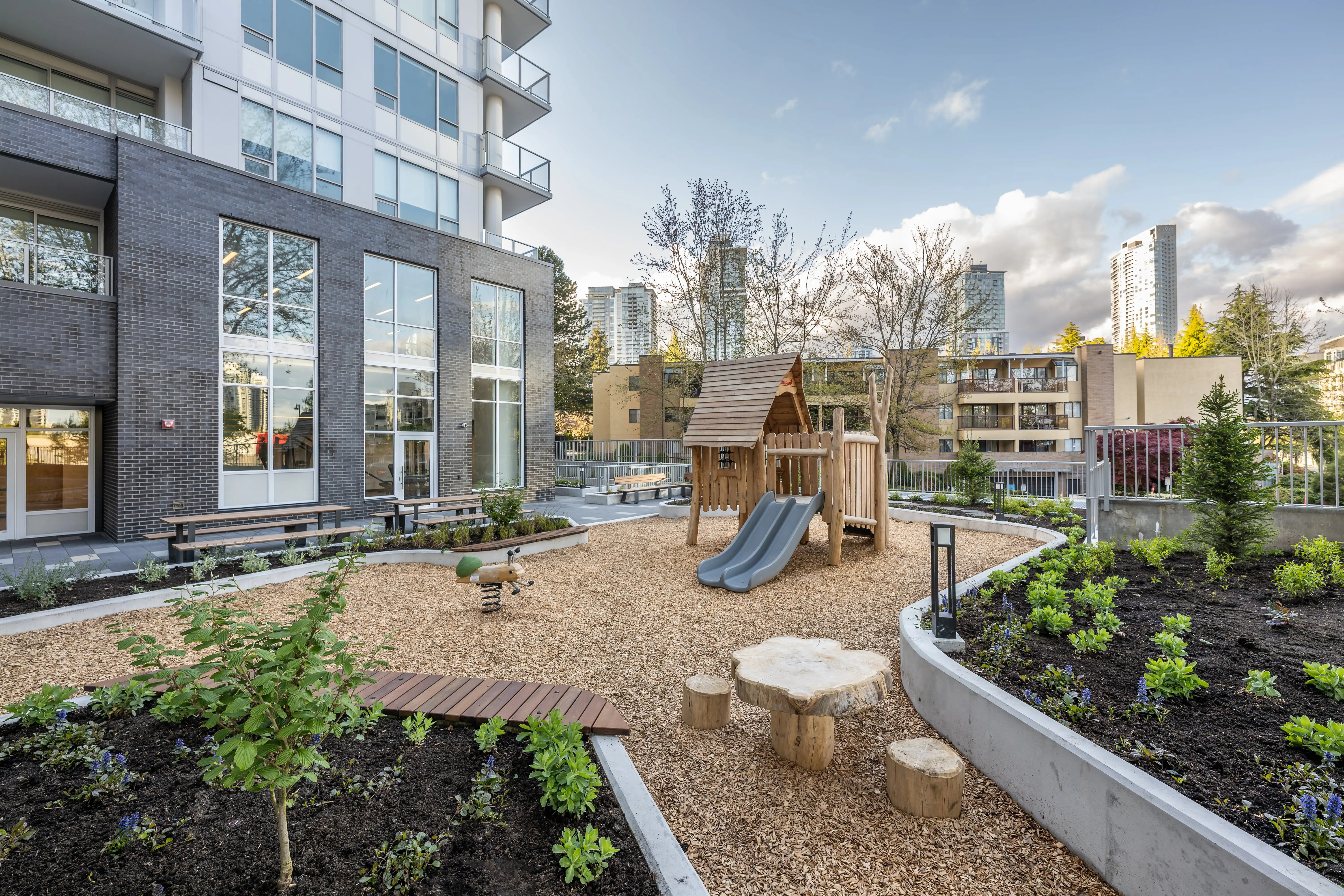 Courtyard play area with slide, playhouse and stump seats at The Holland II