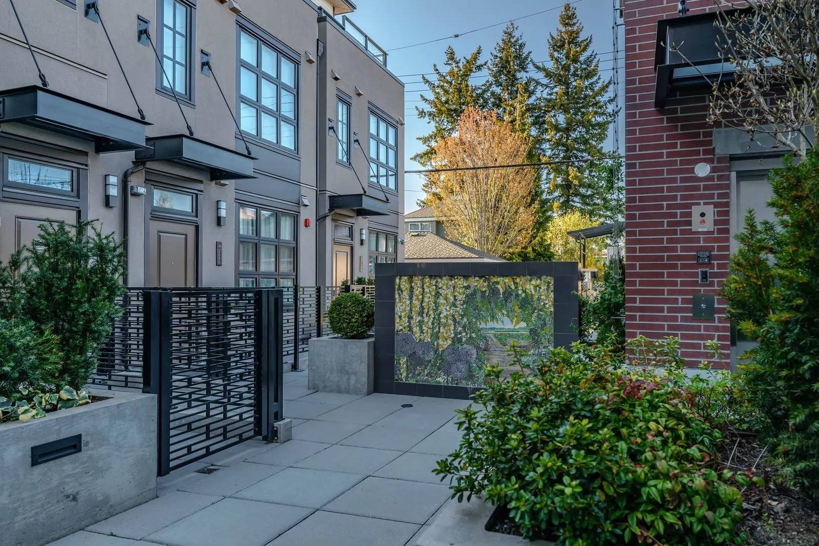 Paved entry court with planters and metal gates at Westbury Townhomes