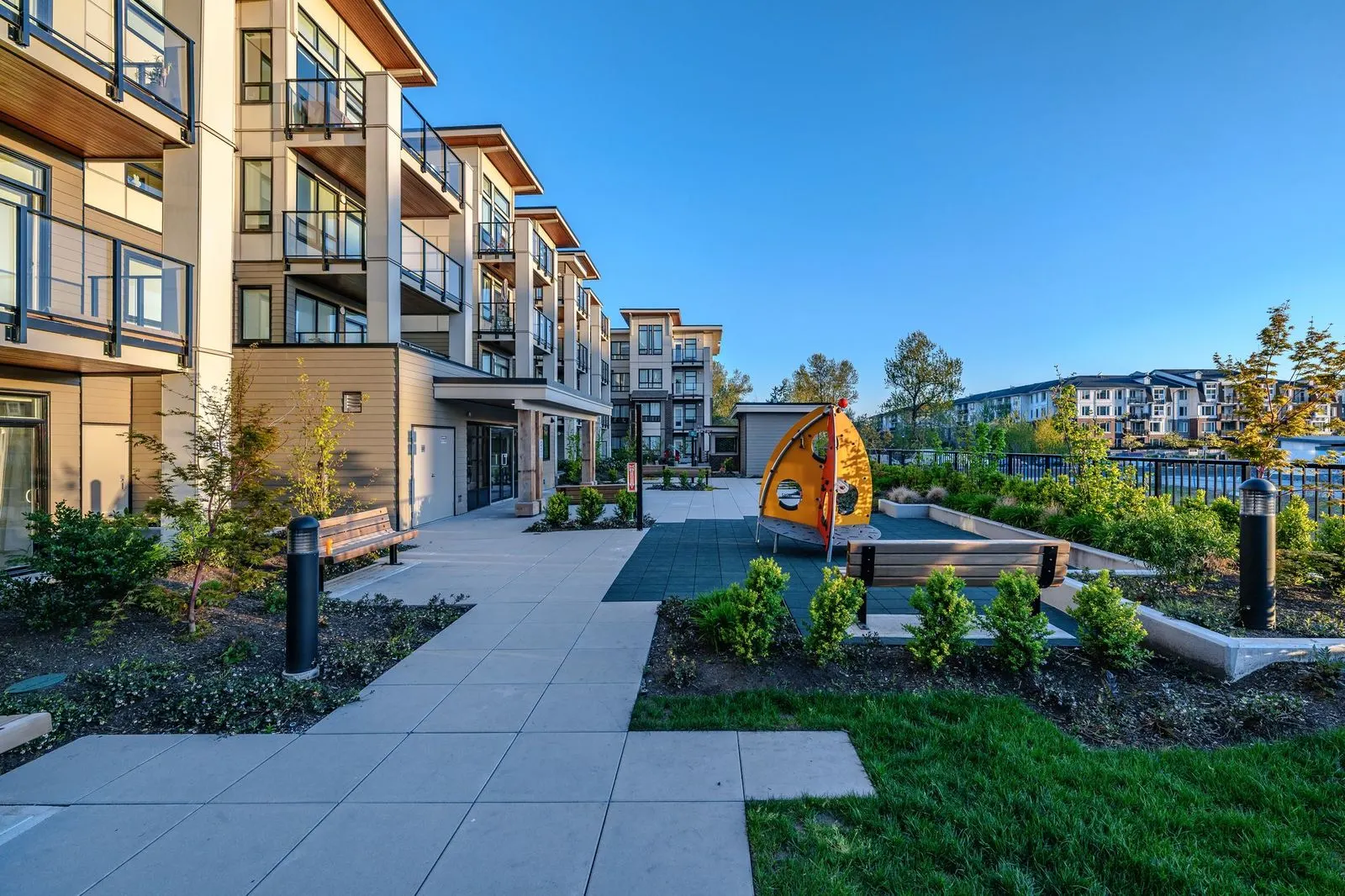 Courtyard walkway with lawn, planting and a play feature at Spark