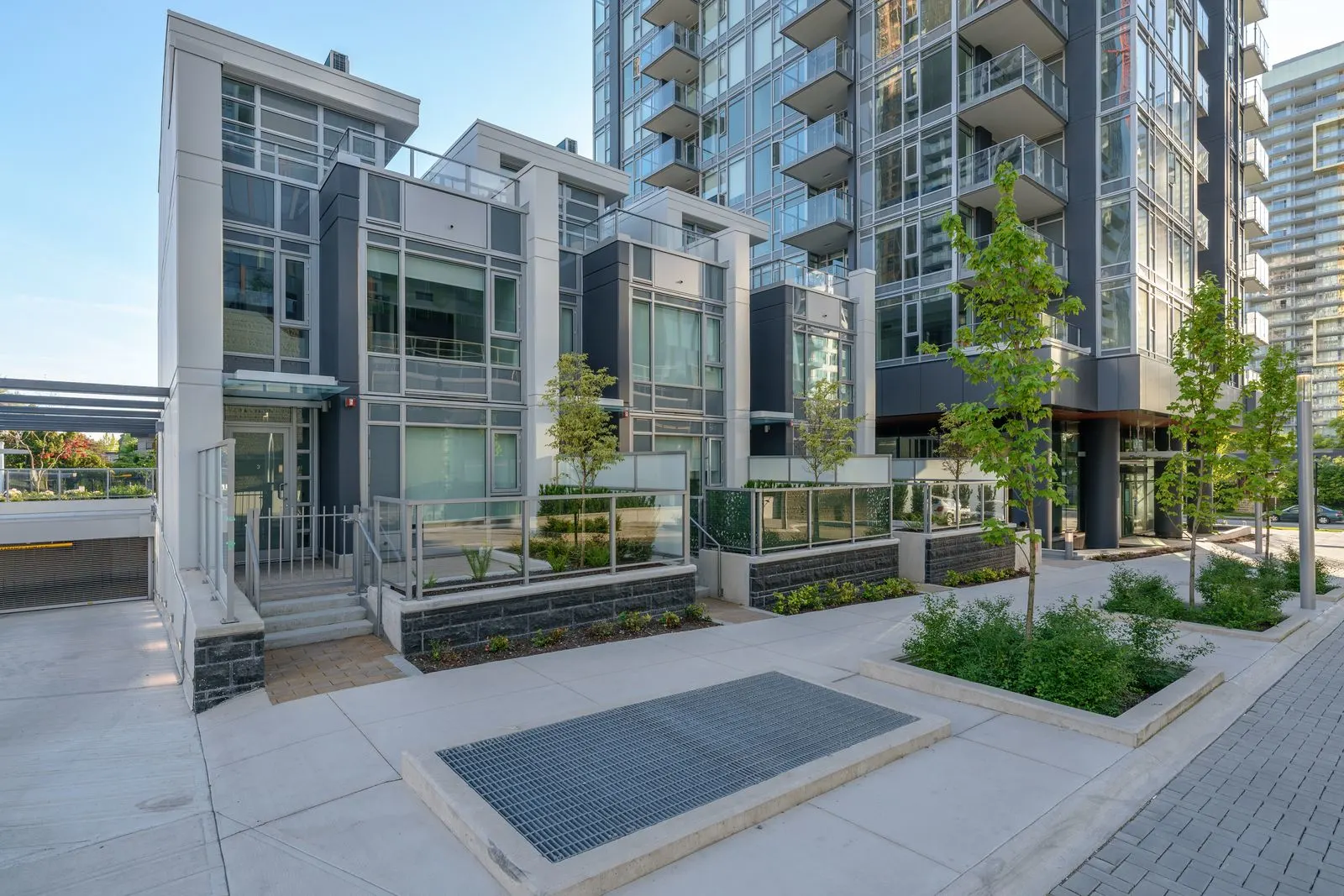 Paved entry plaza with planters at townhomes beneath a tower at Sun Tower II