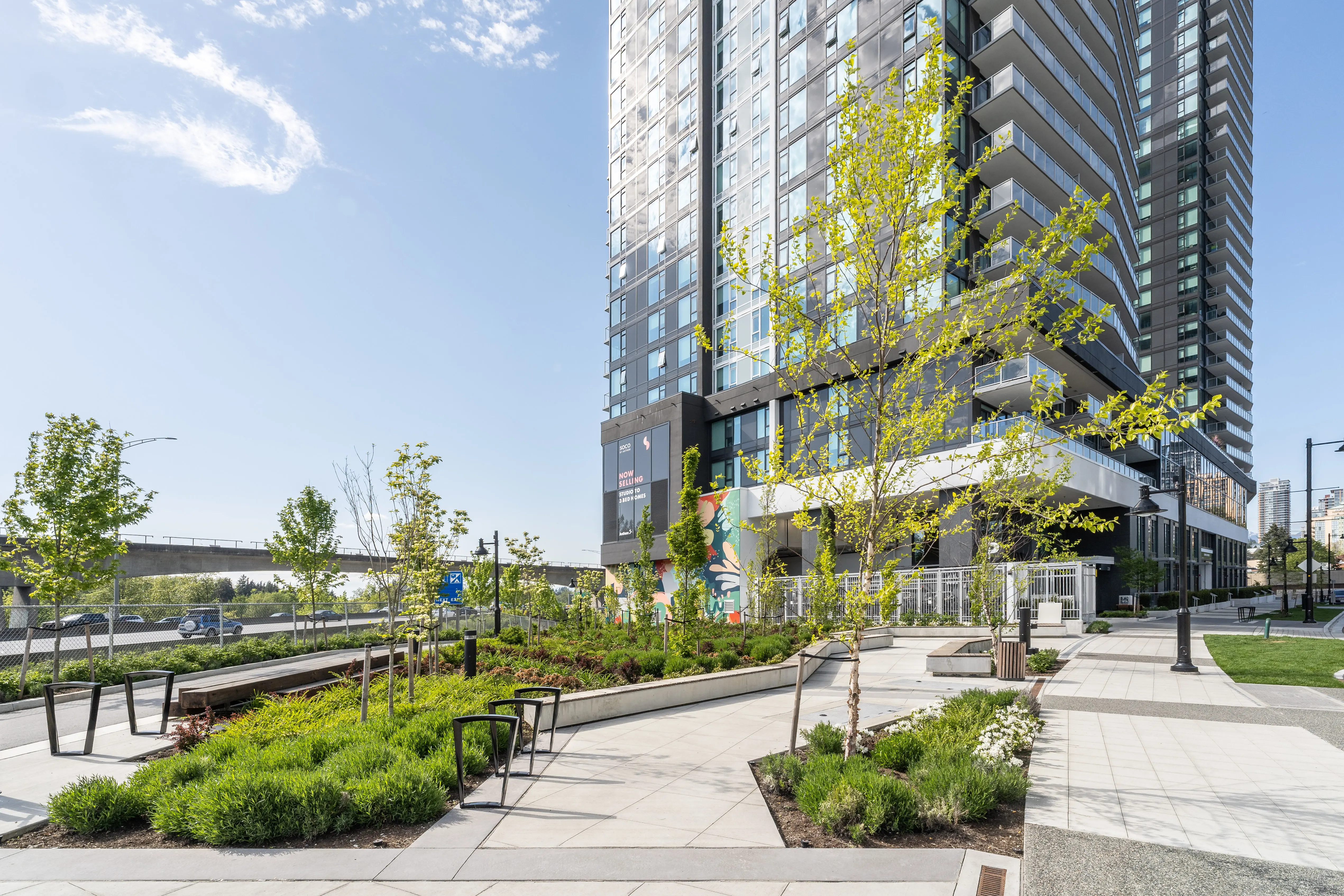 Walkway with benches and planting at the base of a tower at Soco
