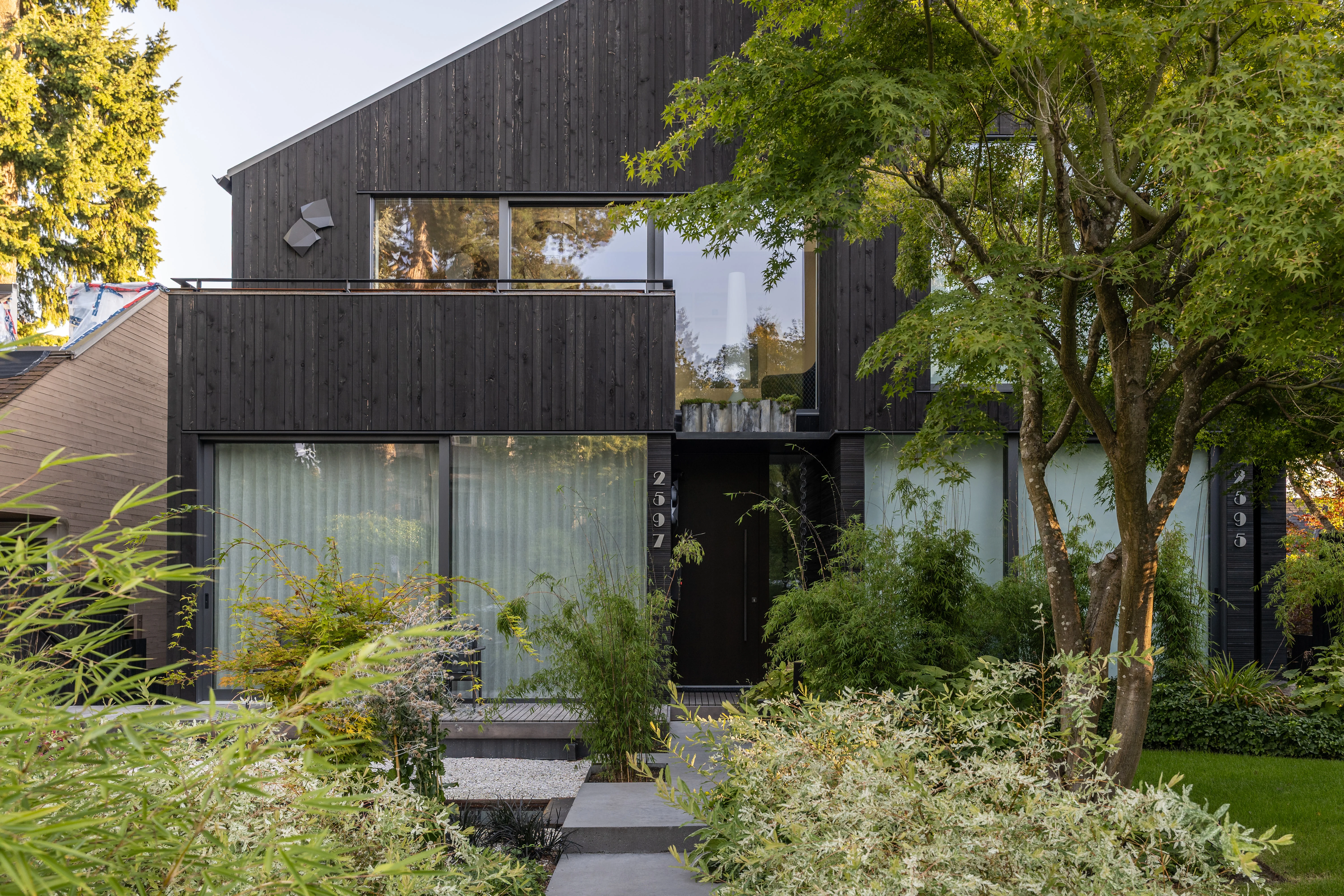 Stepping stone path through planting to a dark-clad house at West 1st