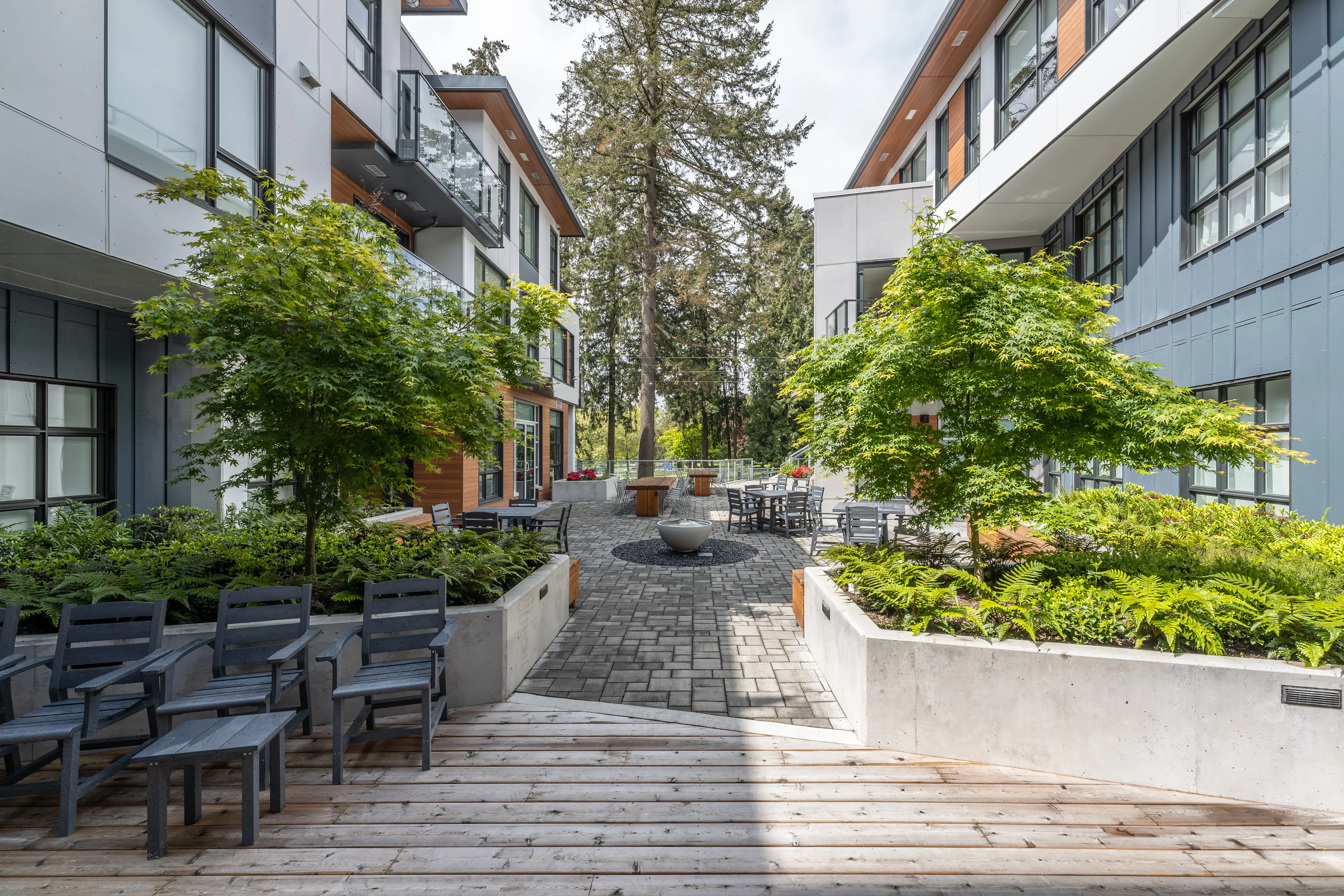 Courtyard with tables, raised planters and trees at L'Arche Community Centre