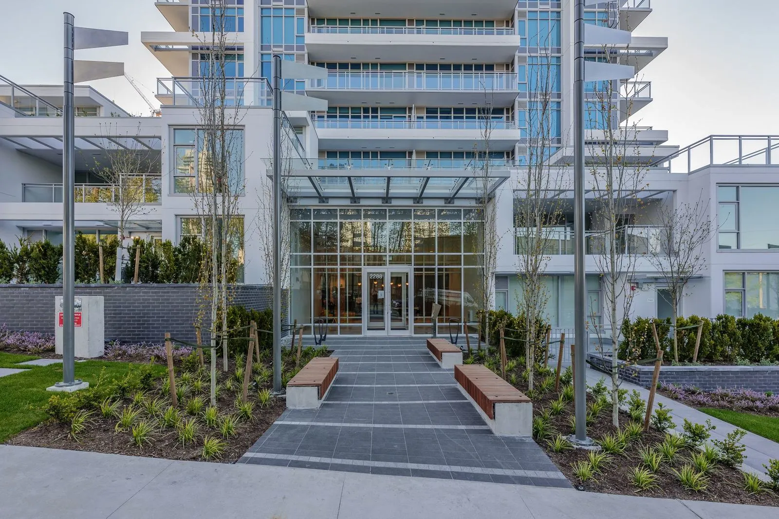 Paved entry walk with planting and benches at a residential tower at Alpha Lumina