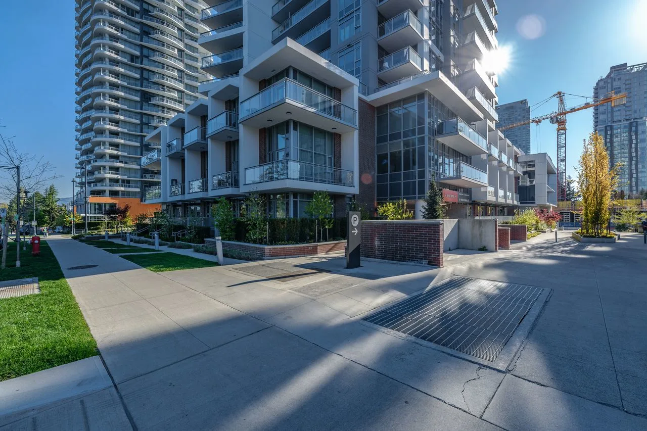 Wide paved walkway and lawn at the base of residential towers at Evolve