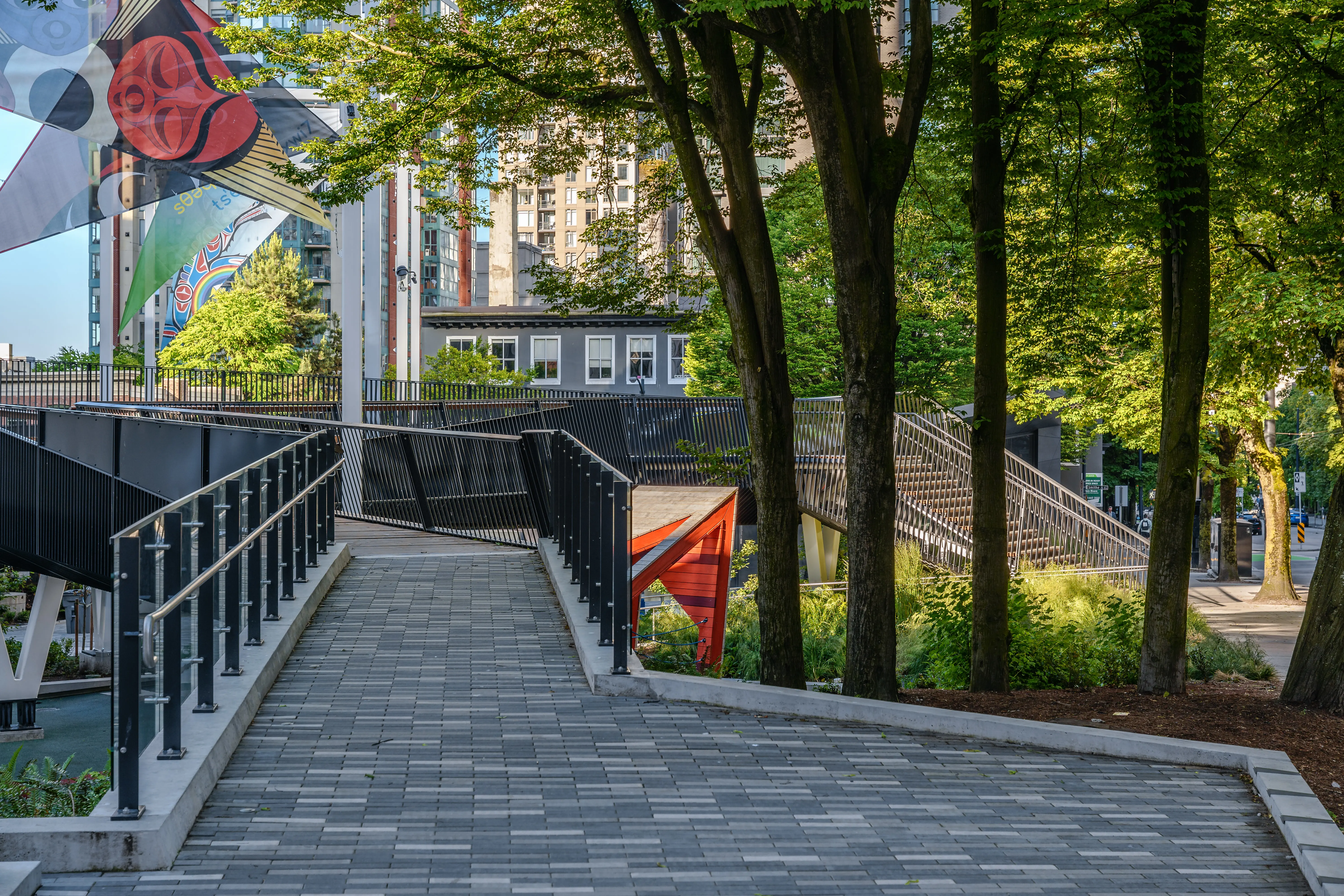 Paved ramp with railings through a treed park at Rainbow Park Downtown