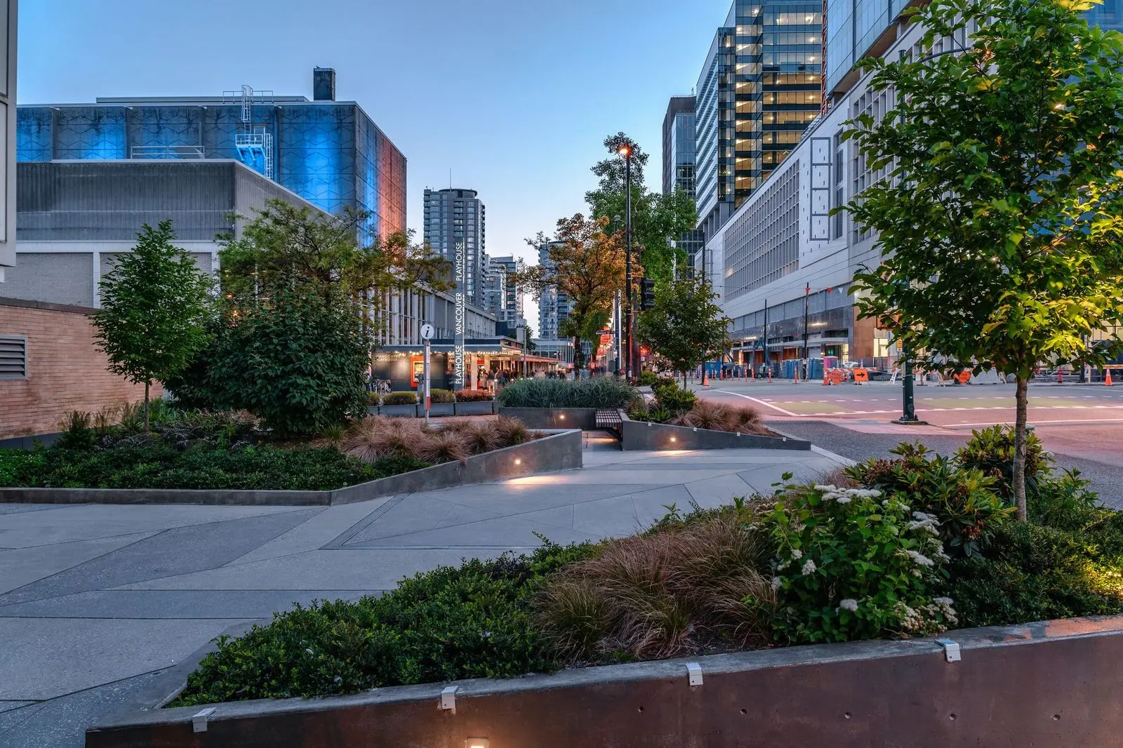 Planting beds and trees along a campus plaza at dusk at Vancouver Community College