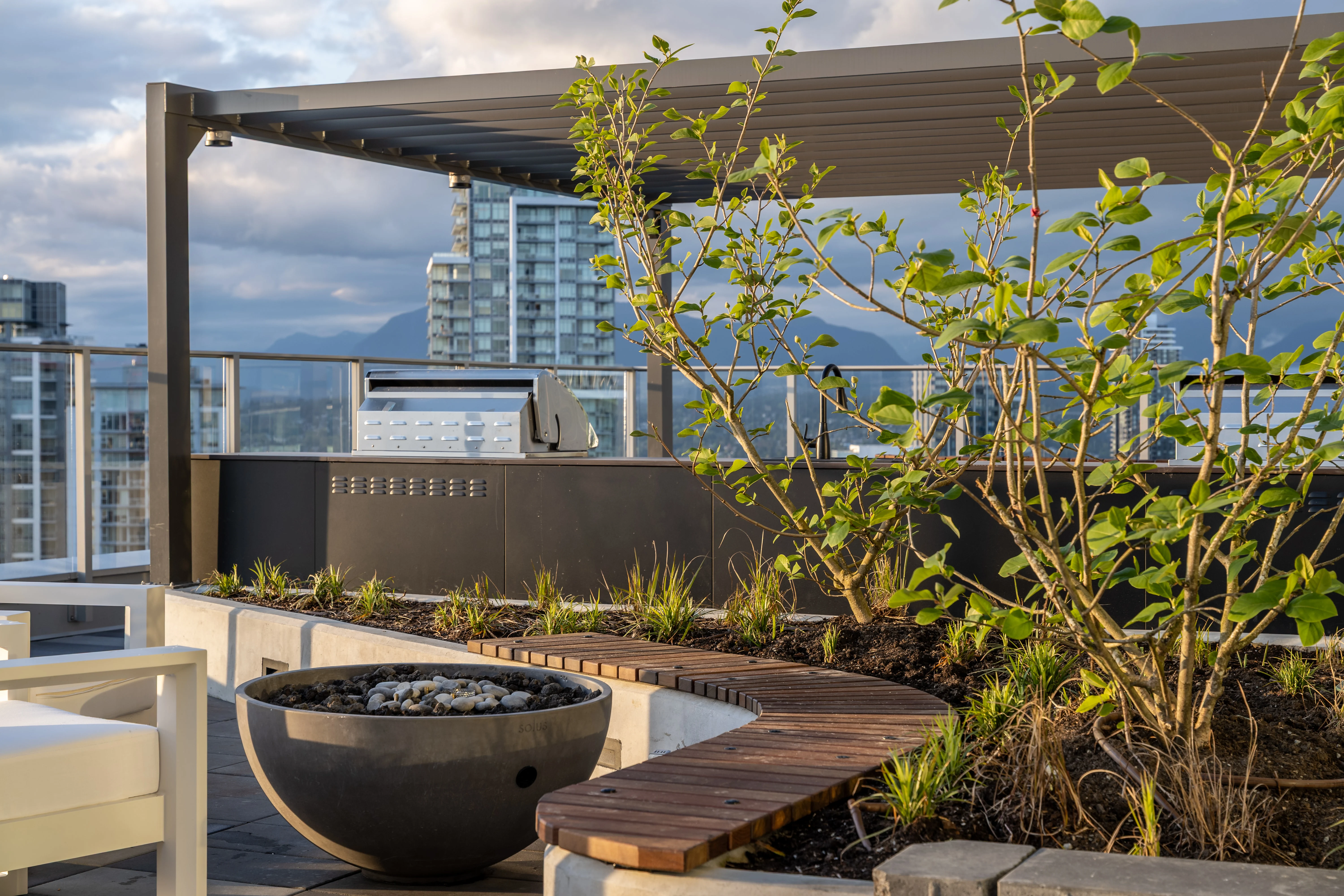 Covered rooftop lounge with fire bowl and planting at The Holland II