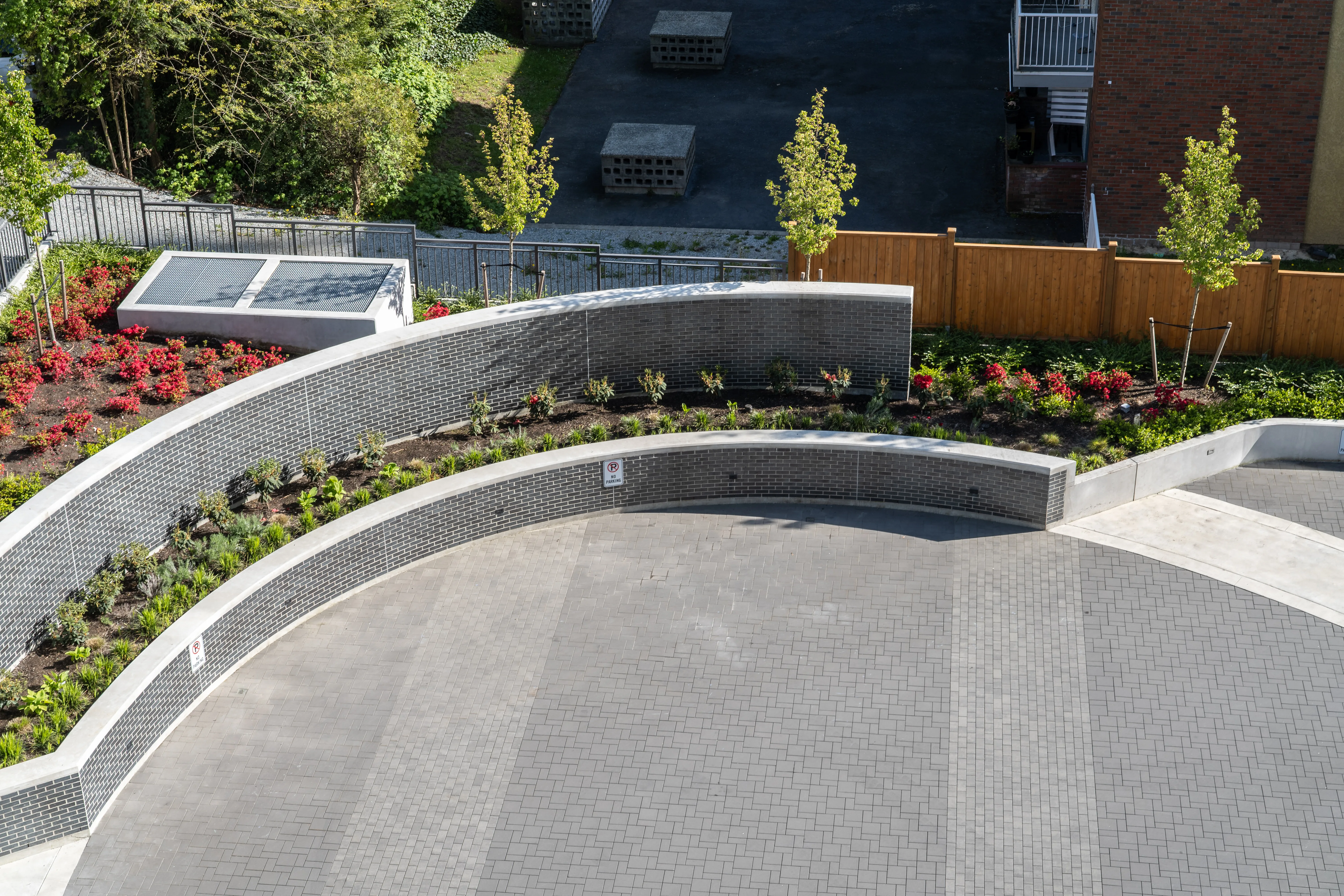 Curved concrete retaining wall and planting around a paved plaza at Precidia