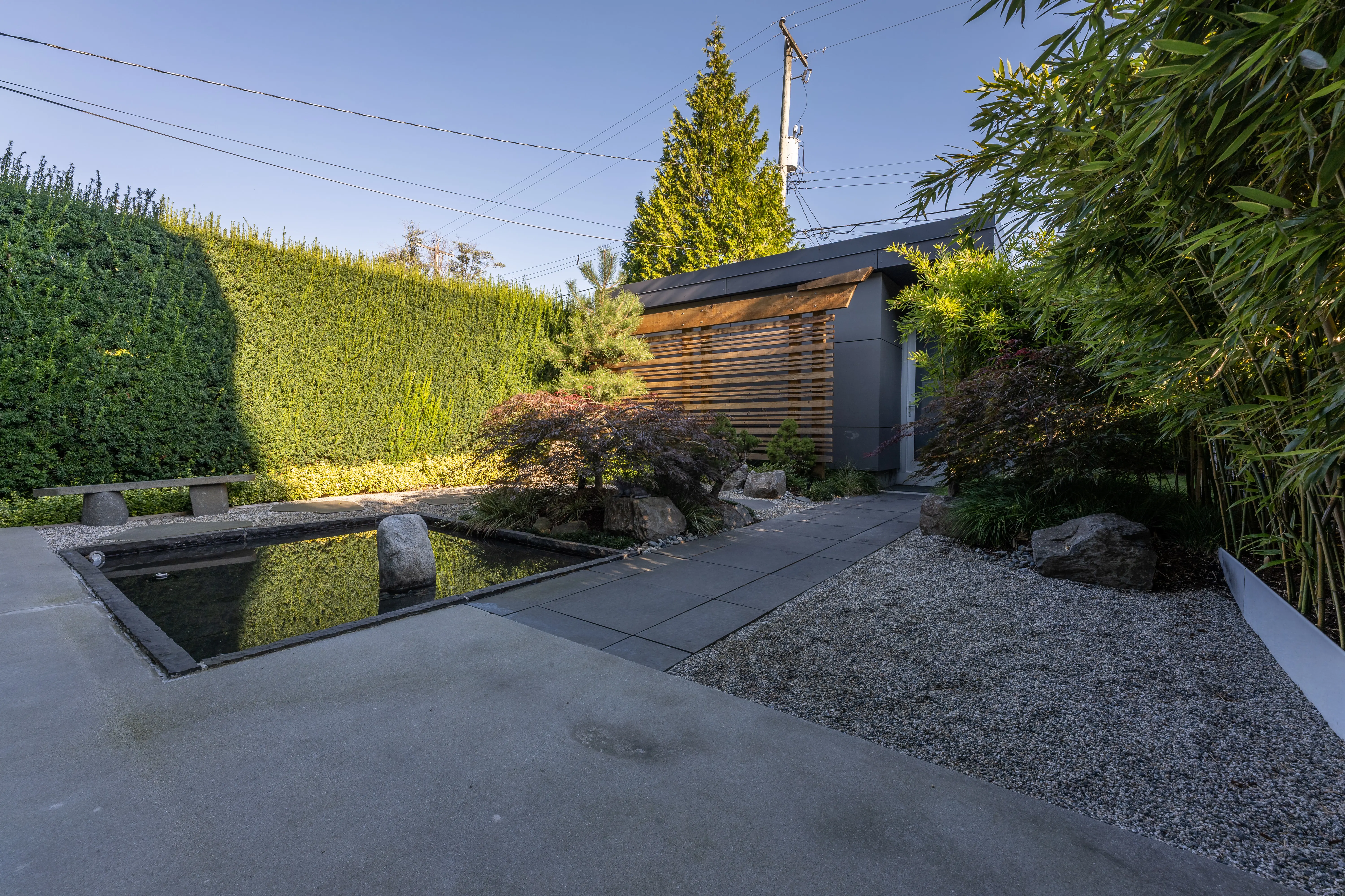 Reflecting pool and gravel garden beside a hedge at West 9th