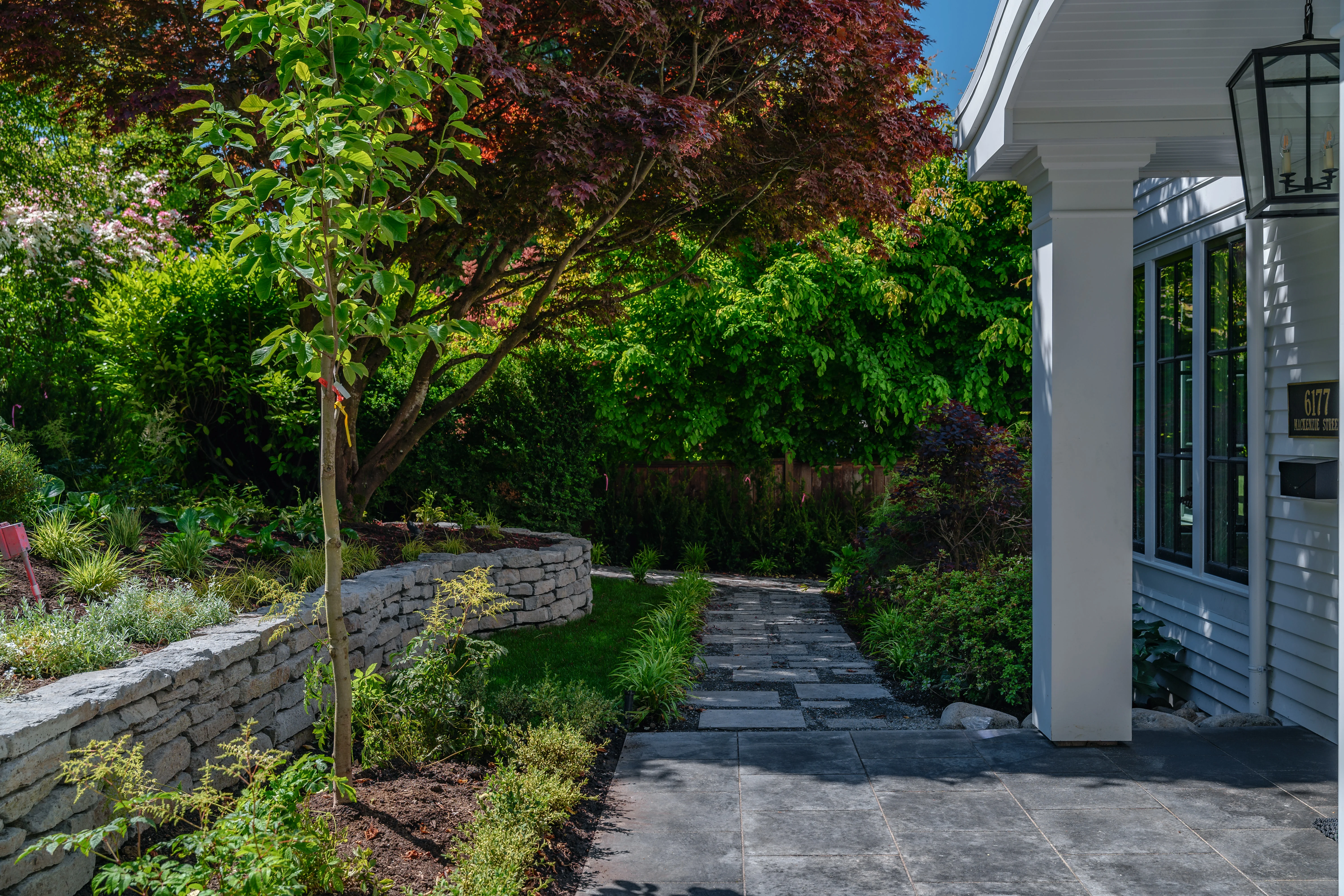 Paved side path with stone wall and planting at MacKenzie