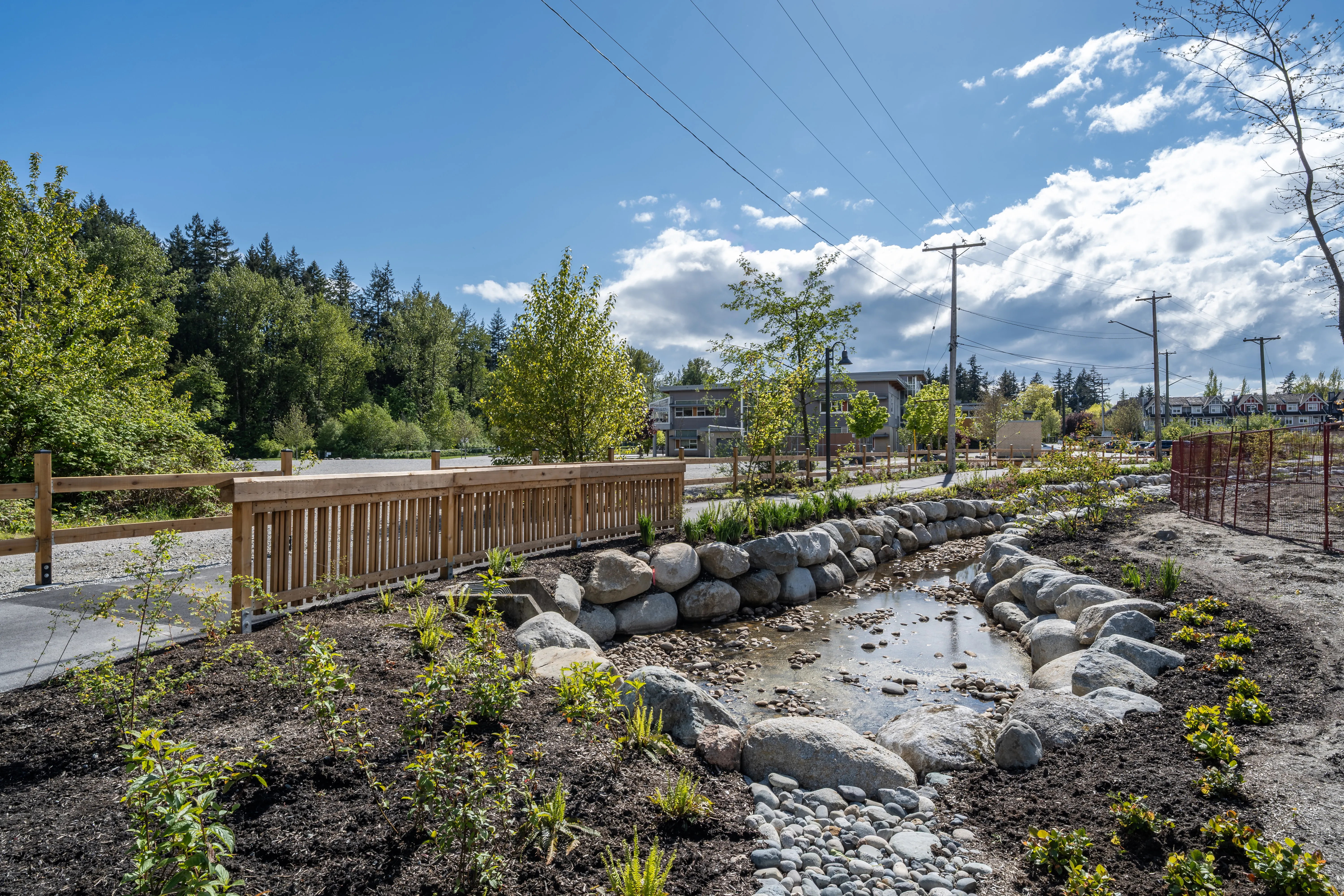 Timber footbridge over a rock-lined swale at Community Green and Ortona Trail