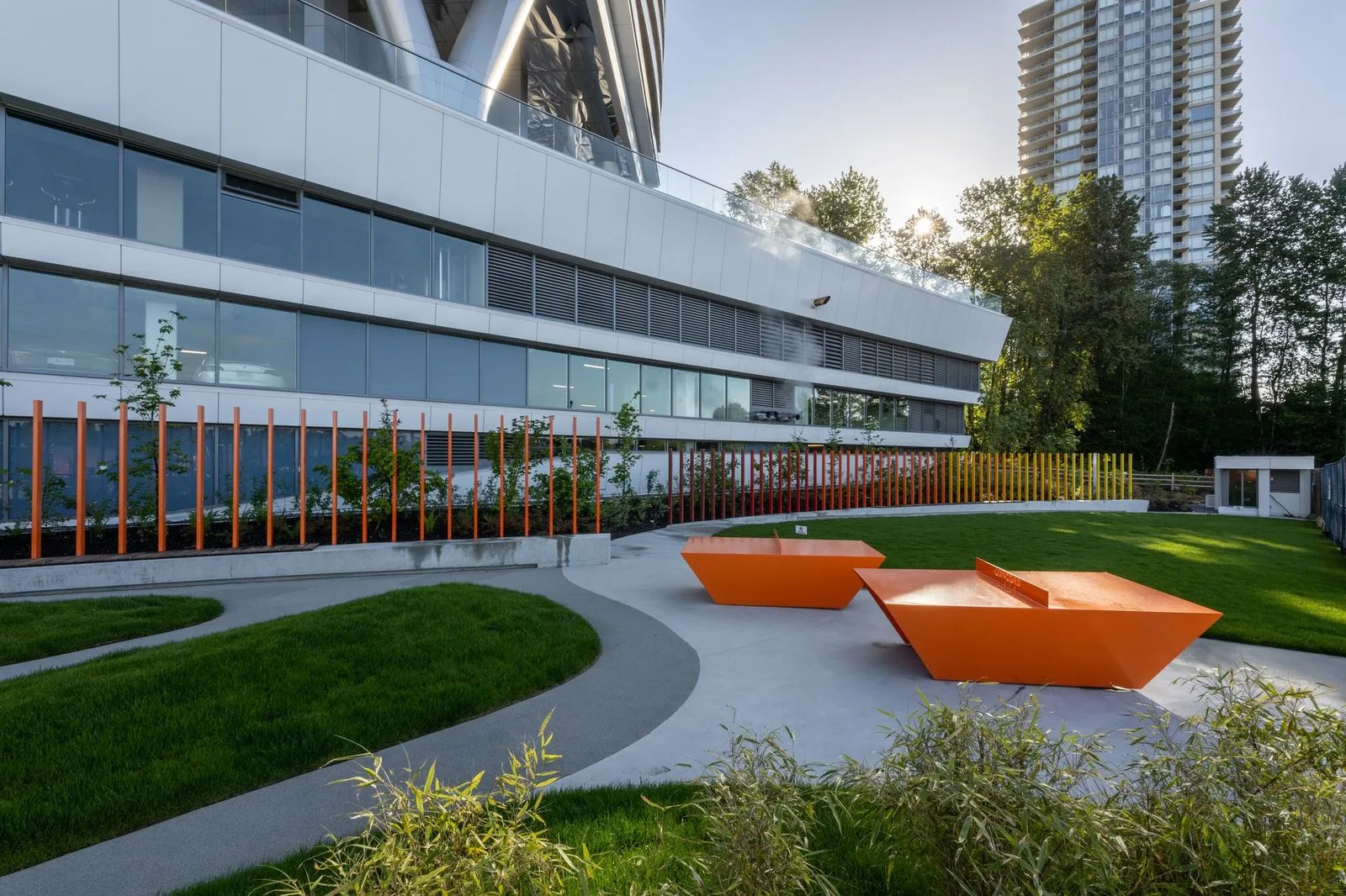 Orange sculptural seating on a plaza beside lawn at Brentwood 1B