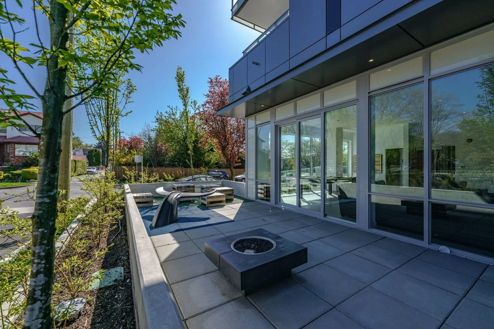 Patio with a fire table beside a planted strip at The Parker