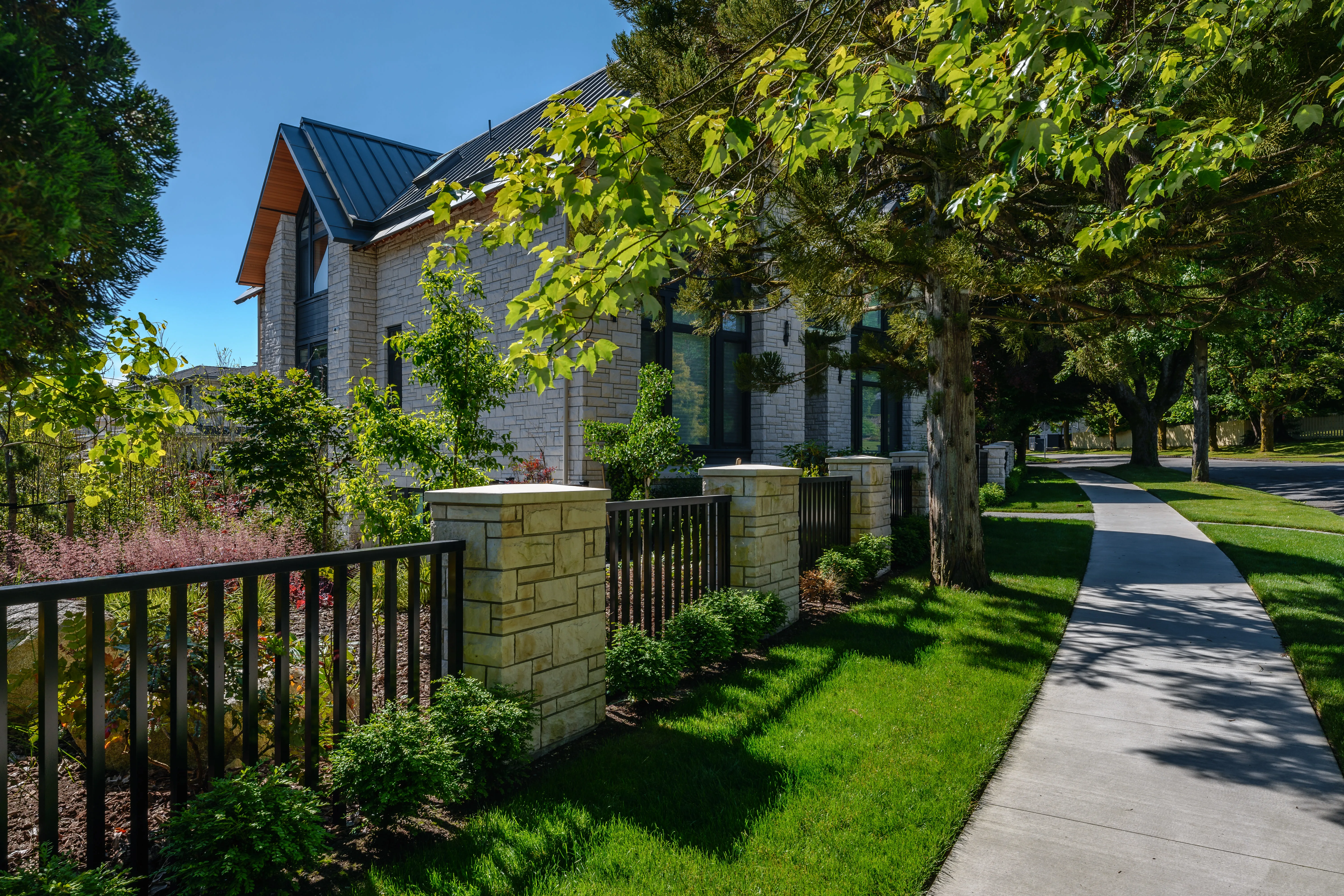 Front lawn, metal fence and walkway under mature trees at Hudson Street